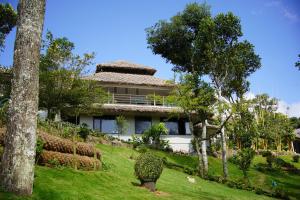 een huis op een heuvel met bomen ervoor bij Blanket Days Resort and Spa in Thekkady