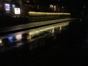 a wet street at night with lights on the street at Ryoso Chatani in Kyoto