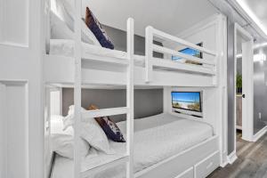 a white bunk bed in a white room with a tv at 1004 Oceanfront Pelican Bch Resort Pools Prime Loc in Destin