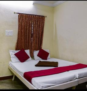 een groot bed met rode kussens in een kamer bij PMS INN in Pondicherry