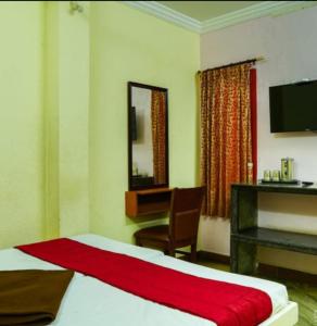 a bedroom with a bed and a desk and a mirror at PMS INN in Puducherry