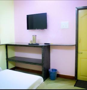 um quarto com uma secretária e uma televisão na parede em PMS INN em Pondicherry