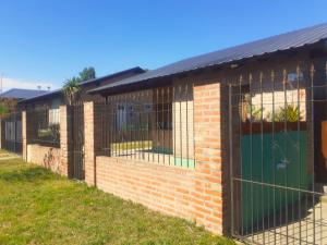 a brick building with a green door and a fence at Casa Monte Hermoso del Este in Monte Hermoso