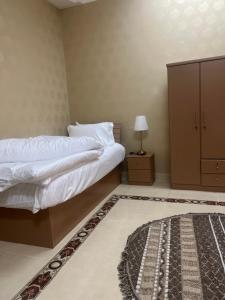 a bedroom with two beds and a cabinet and a rug at دار هند شقق مفروشة بحي سكني in Al Madinah