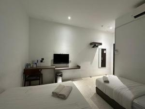 a white bedroom with two beds and a tv at WF Motel in Kulim