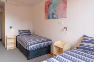 a bedroom with two beds and a painting on the wall at Schuss Alpine Club, Falls Creek in Falls Creek