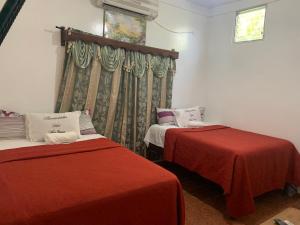 a room with two beds with red sheets and a window at Hotel Marjenny in Copan Ruinas