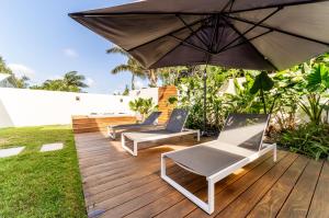 聖若瑟的住宿－Villa moderne Manapany -Jacuzzi-Proximité mer，木制甲板上的两把椅子和一把遮阳伞