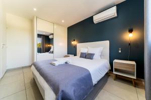 1 dormitorio con 1 cama grande y pared azul en Villa moderne Manapany -Jacuzzi-Proximité mer, en Saint-Joseph