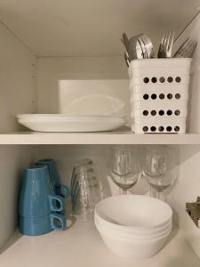 a kitchen shelf with plates and bowls and utensils at City Center Studio Pori in Pori