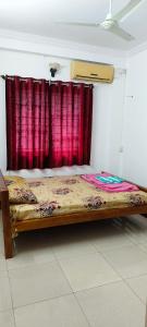 a bed in a room with a red curtain at Prakruthi home stay in Mangalore