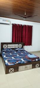 a bed in a room with red curtains at Prakruthi home stay in Mangalore