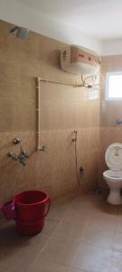 a bathroom with a shower and a toilet and a red bucket at Prakruthi home stay in Mangalore