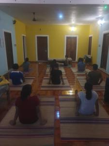 un grupo de personas sentadas en una clase de yoga en Unearth Hostel (Pondicherry) en Auroville