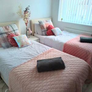 a bedroom with two beds with pink and gray sheets at Tsalach Short Lets in Nottingham
