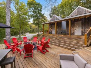 una terraza con sillas rojas y mesas en una casa en Nolin Cabin Experience w/ Hot Tub, en Cub Run