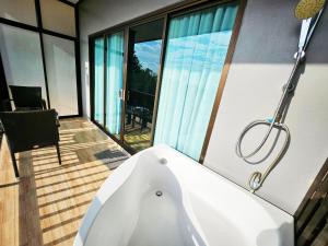 uma banheira na casa de banho com uma varanda em So View Phuket Resort em Ban Sam Kong