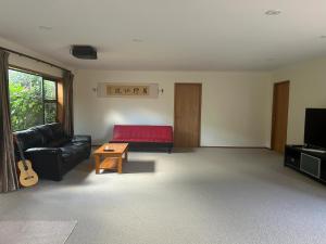 ein Wohnzimmer mit einem roten Sofa und einem Tisch in der Unterkunft Rosie's Farmhouse in Pukekohe East