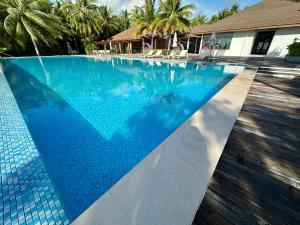 a swimming pool with a blue tiled floor and a house at Fiyavalhu Resort Maldives in Mandhoo