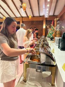 une femme prépare sa nourriture sous forme de buffet dans l'établissement Fiyavalhu Resort Maldives, à Mandhoo