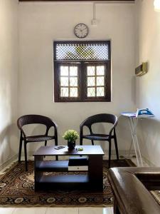 a living room with two chairs and a table and a clock at Kaaya Villa @ Thalawathugoda in Colombo