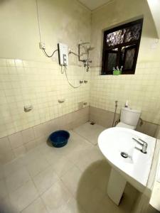 a white bathroom with a toilet and a sink at Kaaya Villa @ Thalawathugoda in Colombo