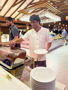 a man holding a plate in front of a grill at Fiyavalhu Resort Maldives in Mandhoo