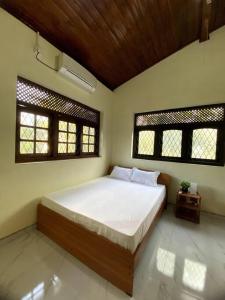 a bedroom with a large bed and two windows at Kaaya Villa @ Thalawathugoda in Colombo