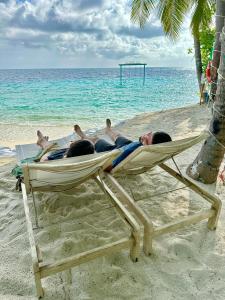a group of people laying in a hammock on the beach at Fiyavalhu Resort Maldives in Mandhoo