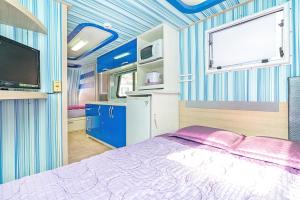 a bedroom with a bed and a tv and blue walls at Gangneung C-cloud caravan in Gangneung