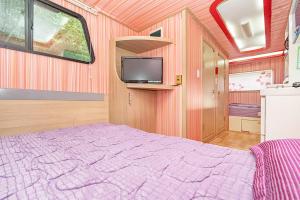 a bedroom with a bed and a tv on the wall at Gangneung C-cloud caravan in Gangneung