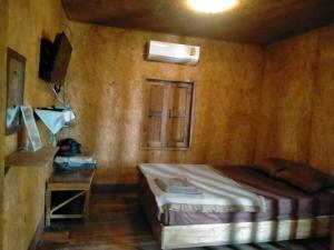 a bedroom with a bed and a table and a window at Sukanyawoodhouse in Ban Tha Rua