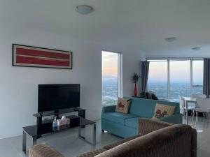 a living room with a blue couch and a tv at Skyline and Mountain View CBD Stay in Gold Coast