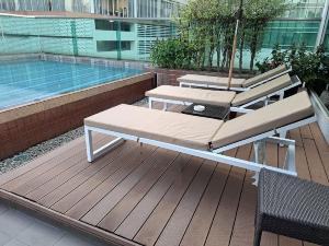 Amora NeoLuxe Suites Hotel في بانكوك: أرجوحة ومظلة على سطح السفينة بجوار حمام سباحة