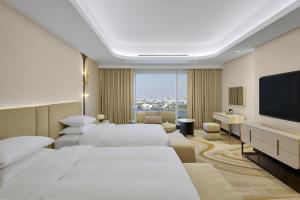 um quarto de hotel com duas camas e uma televisão de ecrã plano em Grand Hyatt Dubai em Dubai