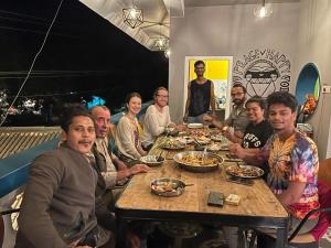 un grupo de personas sentadas alrededor de una mesa comiendo comida en Unearth Hostel (Pondicherry), en Auroville