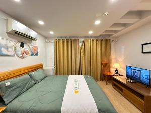a bedroom with a bed and a desk and a television at NEW LAND Apartment 2 - Phu My Hung in Ho Chi Minh City
