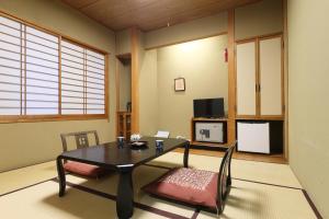 a living room with a table and a tv at Hotel Takamatsu in Kusatsu