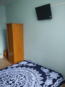 1 dormitorio con 1 cama y TV en la pared en Hotel du Berry en Perpiñán