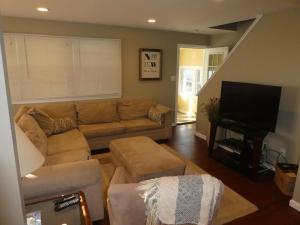 a living room with a couch and a flat screen tv at Bayside Cape, Quiet Street in Beach Haven Crest