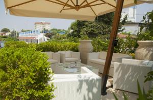 eine Terrasse mit weißen Stühlen und einem Sonnenschirm in der Unterkunft Club Azzurro Hotel & Resort in Porto Cesareo
