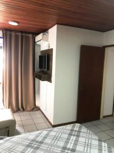 um quarto com uma cama, uma televisão e uma porta em Apartamento Rafaelli em Florianópolis