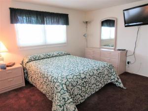 een slaapkamer met een bed, 2 dressoires en een televisie bij 1st Floor Duplex In Brant Beach Just 3 Homes From The Beach in Brant Beach