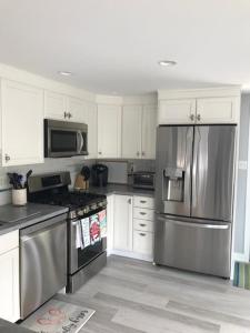 a kitchen with white cabinets and a stainless steel refrigerator at Hear The Ocean From This Well Kept Oceanside Duplex in Brant Beach