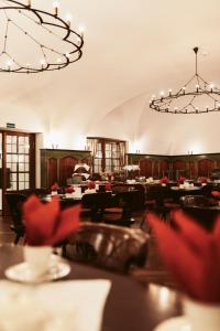 uma sala de jantar com mesas, cadeiras e lustres em Hotel Goldene Sonne em Landshut