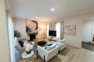 sala de estar con muebles blancos y TV de pantalla plana en Cheerful 4-bedroom home with Park View, en Glen Waverley