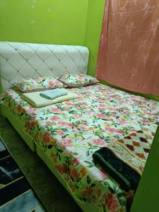 a bed with a floral comforter and a laptop on it at Nas Homestay in Jitra