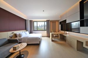 a hotel room with a bed and a couch and a tv at Maison New Century Tongxiang in Tongxiang