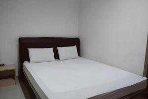 ein Bett mit weißer Bettwäsche und zwei Kissen in der Unterkunft OYO 93536 Pondok Almirah in Mamuju