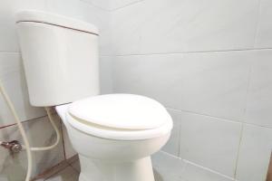 een wit toilet in een wit betegelde badkamer bij OYO 93536 Pondok Almirah in Mamuju